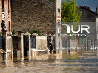 A man pulls water off his house on a flooded street in Coulommiers, Seine-et-Marne department, east of Paris, on October 10, 2024, as the he...