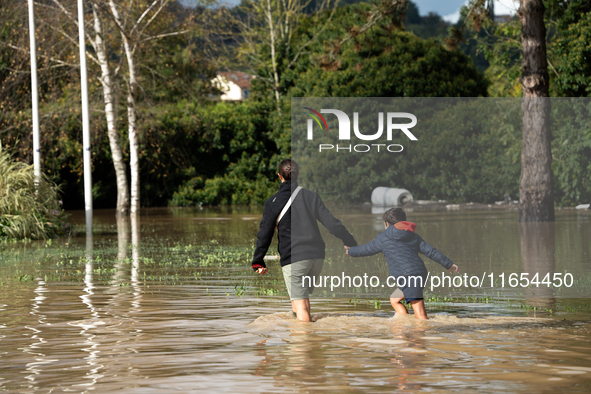 A woman and her child walk down a flooded street in Coulommiers, Seine-et-Marne department, east of Paris, on October 10, 2024, as the heavy...