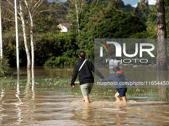 A woman and her child walk down a flooded street in Coulommiers, Seine-et-Marne department, east of Paris, on October 10, 2024, as the heavy...