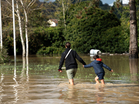 A woman and her child walk down a flooded street in Coulommiers, Seine-et-Marne department, east of Paris, on October 10, 2024, as the heavy...