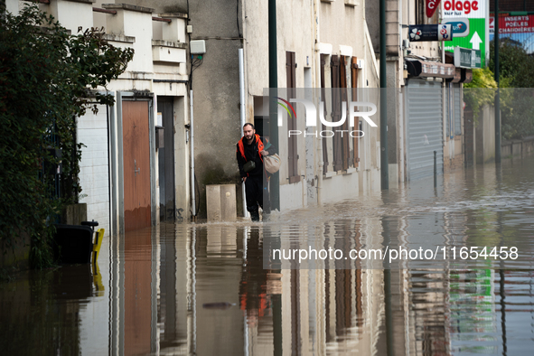 A man walks down a flooded street in Coulommiers, Seine-et-Marne department, east of Paris, on October 10, 2024, as the heavy rains associat...