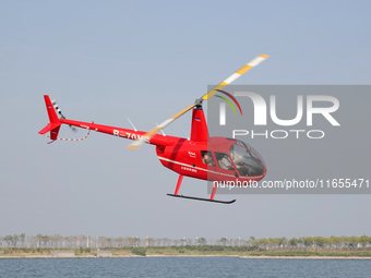 A Tianjin Jinjintong R44 helicopter performs a sightseeing flight in Binhai New Area, Tianjin, China, on October 4, 2023. The Civil Aviation...