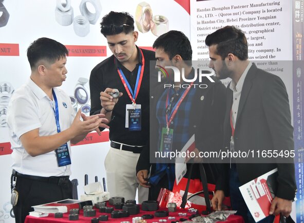 An exhibitor introduces fastener product information to foreign merchants at the 2024 International Procurement Conference in Handan, China,...