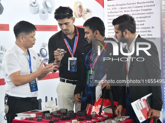 An exhibitor introduces fastener product information to foreign merchants at the 2024 International Procurement Conference in Handan, China,...