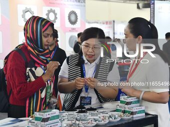 An exhibitor introduces fastener product information to foreign merchants at the 2024 International Procurement Conference in Handan, China,...