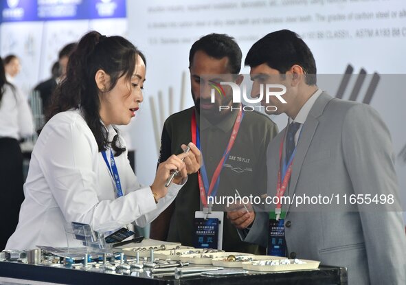 An exhibitor introduces fastener product information to foreign merchants at the 2024 International Procurement Conference in Handan, China,...