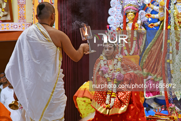 A priest of the Ramakrishna Mission performs arati for a living goddess Kumari in front of a clay image of the Hindu goddess Durga during a...