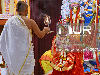 A priest of the Ramakrishna Mission performs arati for a living goddess Kumari in front of a clay image of the Hindu goddess Durga during a...