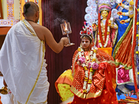 A priest of the Ramakrishna Mission performs arati for a living goddess Kumari in front of a clay image of the Hindu goddess Durga during a...