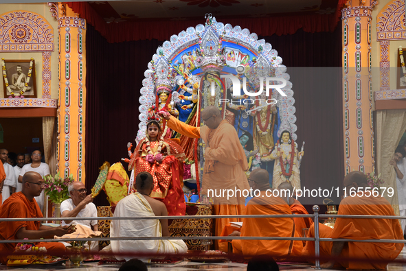 A priest of the Ramakrishna Mission performs a ritual for a living goddess Kumari in front of a clay image of the Hindu goddess Durga during...