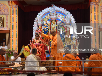 A priest of the Ramakrishna Mission performs a ritual for a living goddess Kumari in front of a clay image of the Hindu goddess Durga during...