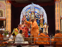 A priest of the Ramakrishna Mission performs a ritual for a living goddess Kumari in front of a clay image of the Hindu goddess Durga during...