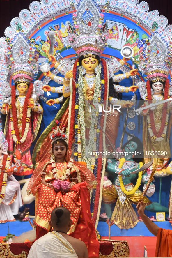 A priest of the Ramakrishna Mission performs a ritual for a living goddess Kumari in front of a clay image of the Hindu goddess Durga during...