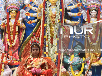 A priest of the Ramakrishna Mission performs a ritual for a living goddess Kumari in front of a clay image of the Hindu goddess Durga during...