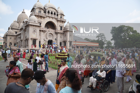 Devotees attend to watch a priest of the Ramakrishna Mission perform arati for a living goddess Kumari in front of a clay image of the Hindu...