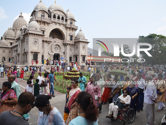 Devotees attend to watch a priest of the Ramakrishna Mission perform arati for a living goddess Kumari in front of a clay image of the Hindu...