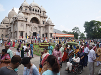 Devotees attend to watch a priest of the Ramakrishna Mission perform arati for a living goddess Kumari in front of a clay image of the Hindu...