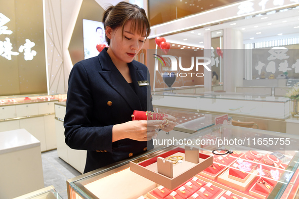 A staff member arranges gold ornaments at a gold shop in Renhuai, China, on October 11, 2024. 