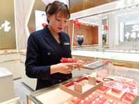 A staff member arranges gold ornaments at a gold shop in Renhuai, China, on October 11, 2024. (