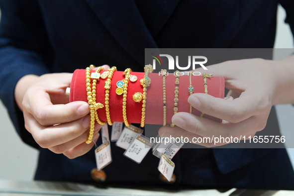 A staff member arranges gold ornaments at a gold shop in Renhuai, China, on October 11, 2024. 