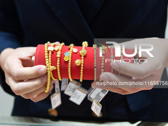 A staff member arranges gold ornaments at a gold shop in Renhuai, China, on October 11, 2024. (