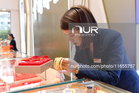 A staff member arranges gold ornaments at a gold shop in Renhuai, China, on October 11, 2024. 