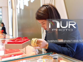 A staff member arranges gold ornaments at a gold shop in Renhuai, China, on October 11, 2024. (