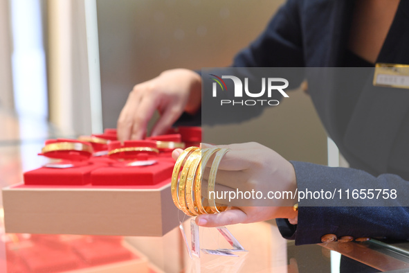 A staff member arranges gold ornaments at a gold shop in Renhuai, China, on October 11, 2024. 