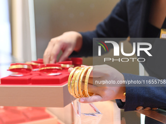 A staff member arranges gold ornaments at a gold shop in Renhuai, China, on October 11, 2024. (