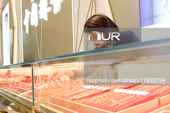 A staff member arranges gold ornaments at a gold shop in Renhuai, China, on October 11, 2024. 