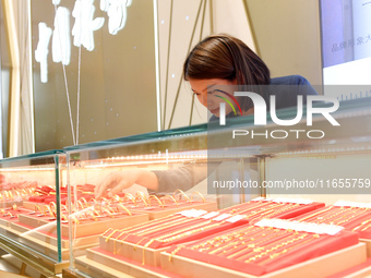 A staff member arranges gold ornaments at a gold shop in Renhuai, China, on October 11, 2024. (