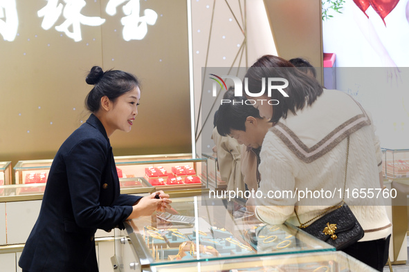 Consumers shop for gold jewelry at a gold store in Renhuai, China, on October 11, 2024. 