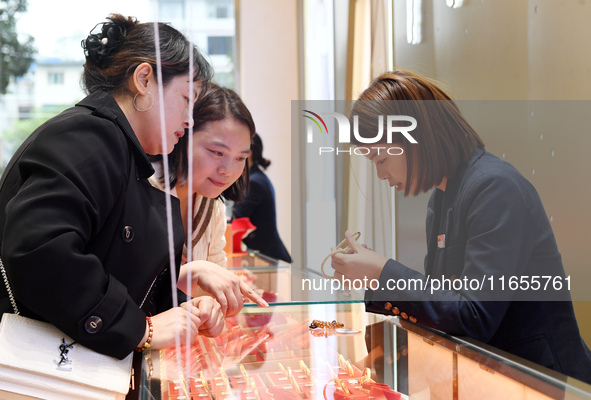 Consumers shop for gold jewelry at a gold store in Renhuai, China, on October 11, 2024. 