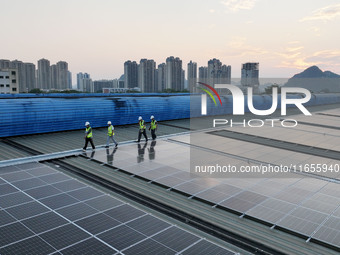 Technicians check photovoltaic power generation equipment before it is connected to the grid for power supply in Liuzhou, China, on October...