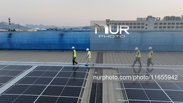 Technicians check photovoltaic power generation equipment before it is connected to the grid for power supply in Liuzhou, China, on October...