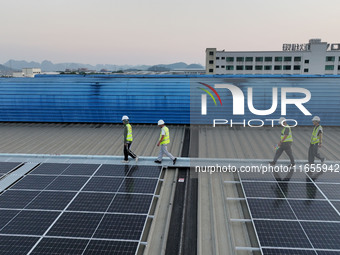 Technicians check photovoltaic power generation equipment before it is connected to the grid for power supply in Liuzhou, China, on October...