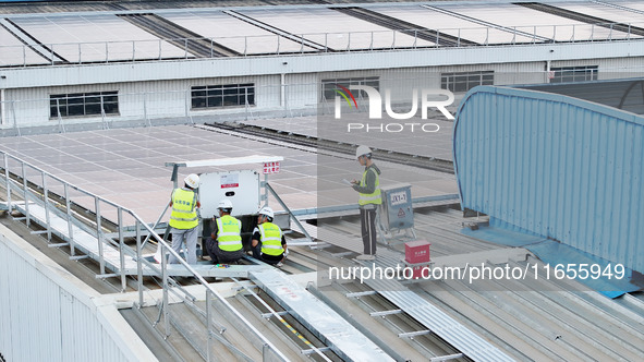 Technicians check photovoltaic power generation equipment before it is connected to the grid for power supply in Liuzhou, China, on October...