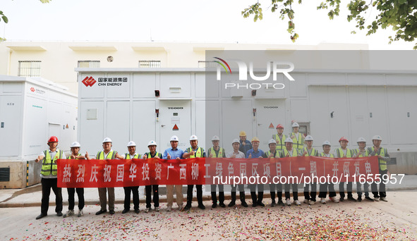 Engineers and technicians pose for a group photo after they successfully connect to the grid for power generation in Liuzhou, Guangxi Zhuang...