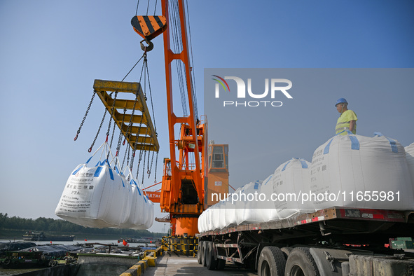 A crane transfers phthalic acid to a truck at the eastern operation area of Siyang Port on the Beijing-Hangzhou Grand Canal in Suqian, China...