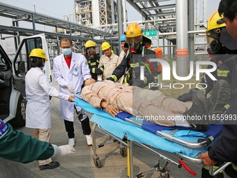 Rescue workers evacuate injured employees during an emergency drill for a fire accident involving a leaking hazardous chemical tank farm in...