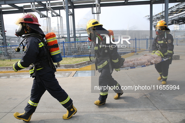 Rescue workers evacuate injured employees during an emergency drill for a fire accident involving a leaking hazardous chemical tank farm in...