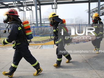 Rescue workers evacuate injured employees during an emergency drill for a fire accident involving a leaking hazardous chemical tank farm in...