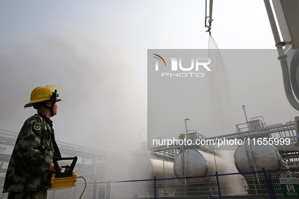 Firefighters operate a fire cannon to spray a fire during an emergency drill for a leaking fire at a hazardous chemical tank farm in Lianyun...