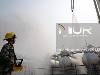 Firefighters operate a fire cannon to spray a fire during an emergency drill for a leaking fire at a hazardous chemical tank farm in Lianyun...