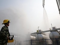 Firefighters operate a fire cannon to spray a fire during an emergency drill for a leaking fire at a hazardous chemical tank farm in Lianyun...