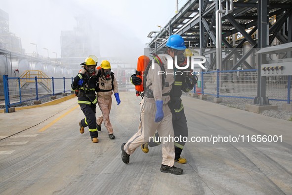 Rescue workers evacuate injured employees during an emergency drill for a fire accident involving a leaking hazardous chemical tank farm in...