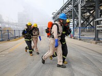 Rescue workers evacuate injured employees during an emergency drill for a fire accident involving a leaking hazardous chemical tank farm in...