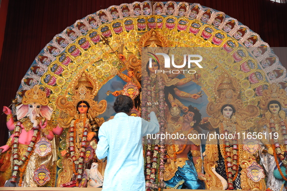 A Hindu priest holds a lamp while praying in front of an idol of Durga during a ritual known as Aarti inside a ''pandal'' or temporary platf...