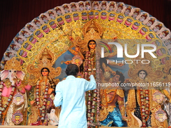 A Hindu priest holds a lamp while praying in front of an idol of Durga during a ritual known as Aarti inside a ''pandal'' or temporary platf...