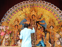 A Hindu priest holds a lamp while praying in front of an idol of Durga during a ritual known as Aarti inside a ''pandal'' or temporary platf...